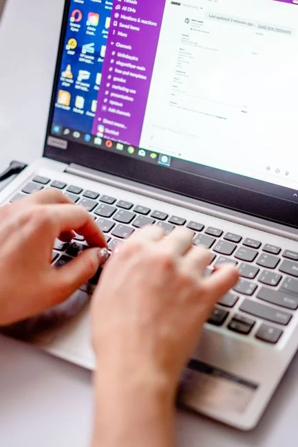 A person using a laptop with an elegant tote bag nearby in a casual setting.